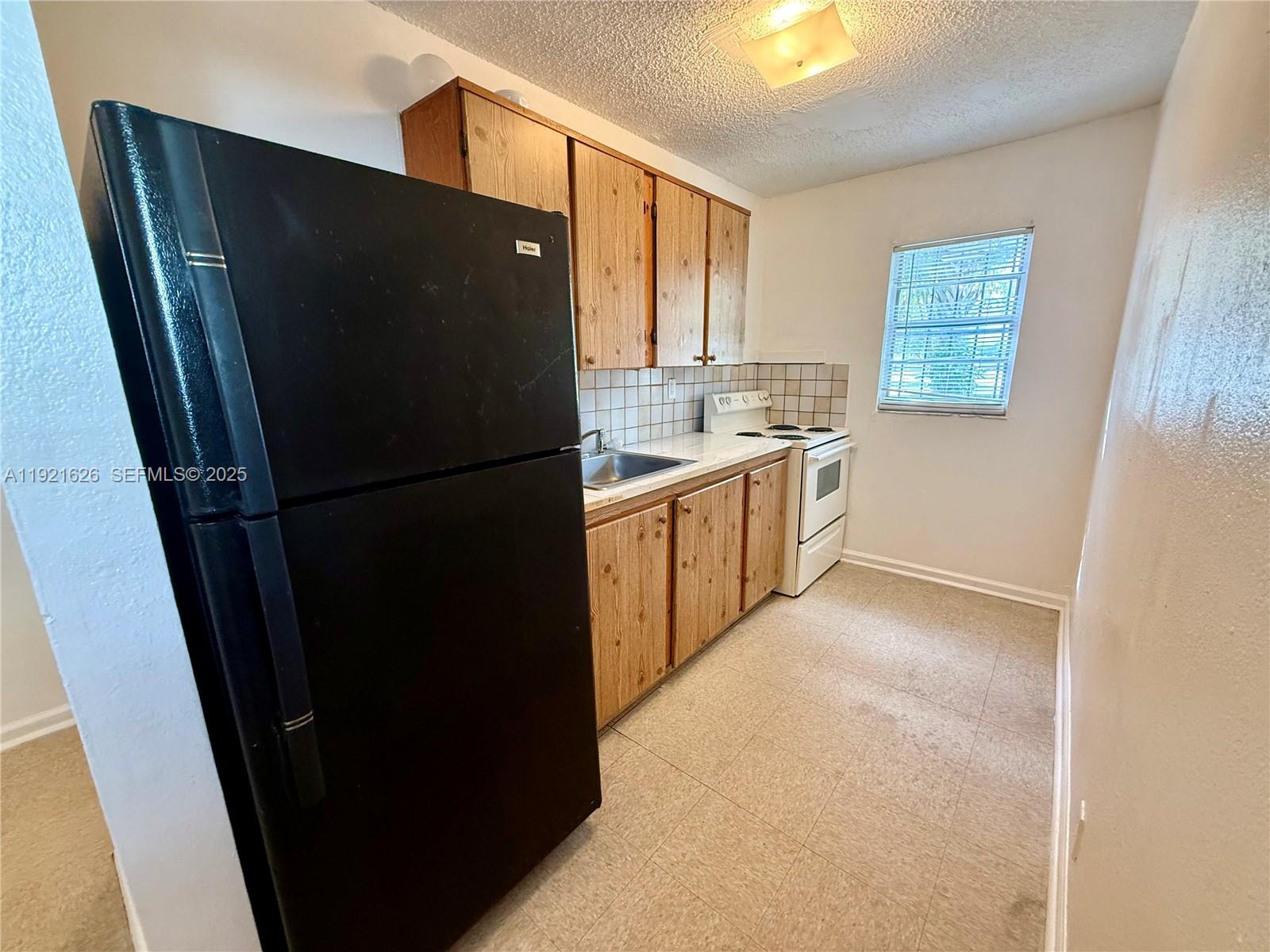 724 Southwest 11th Avenue, Unit 1 Miami, FL 33130 - Photo 3 of 7 a kitchen with granite countertop stainless steel appliances a refrigerator a sink and a cabinets