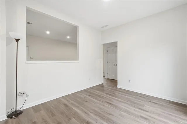 a view of an empty room with wooden floor and a ceiling fan