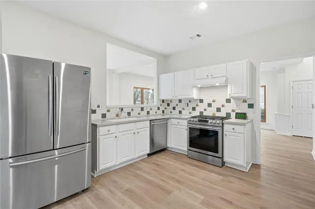 a kitchen with stainless steel appliances white cabinets and wooden floors