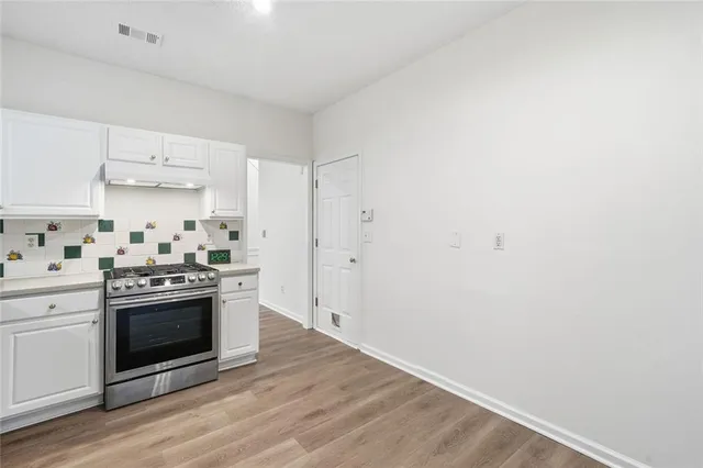 a kitchen with cabinets stainless steel appliances and wooden floor