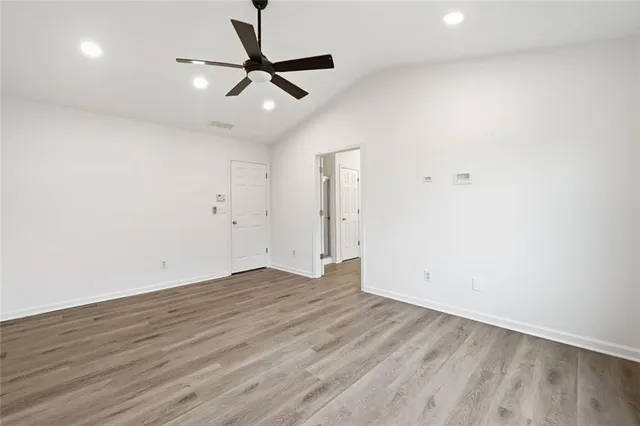 an empty room with wooden floor fan and windows