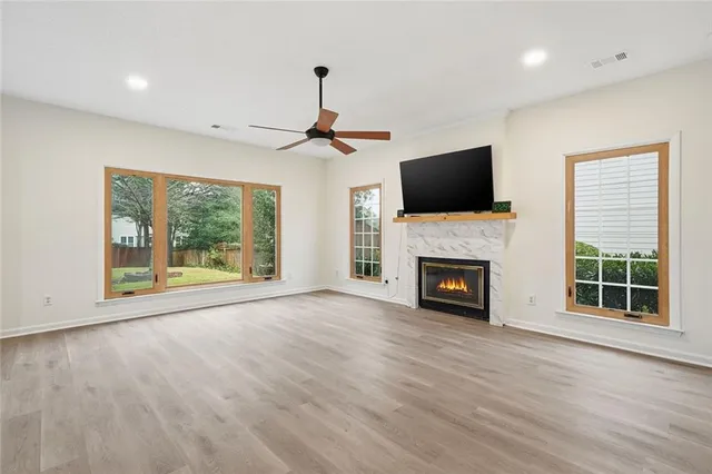 a view of a livingroom with a fireplace wooden floor and windows