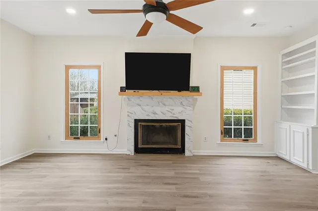 a view of an empty room with wooden floor fireplace and a window