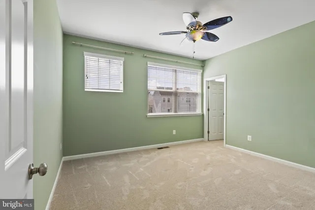 a view of a livingroom with a ceiling fan & windows