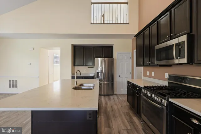 a kitchen with stainless steel appliances a sink dishwasher stove top oven and wooden floor