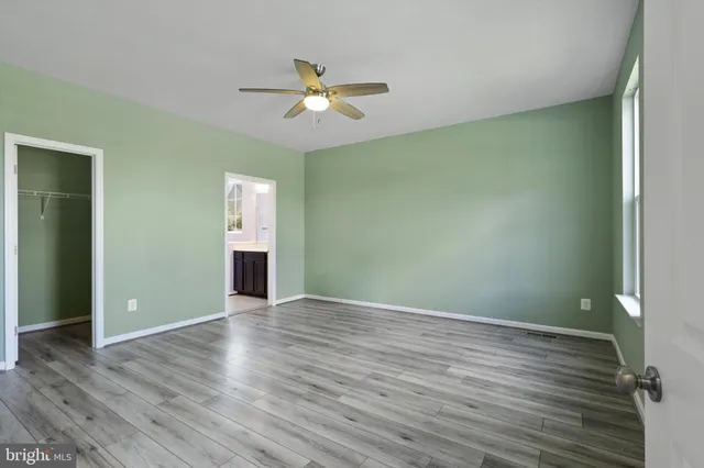 an empty room with wooden floor fan and windows