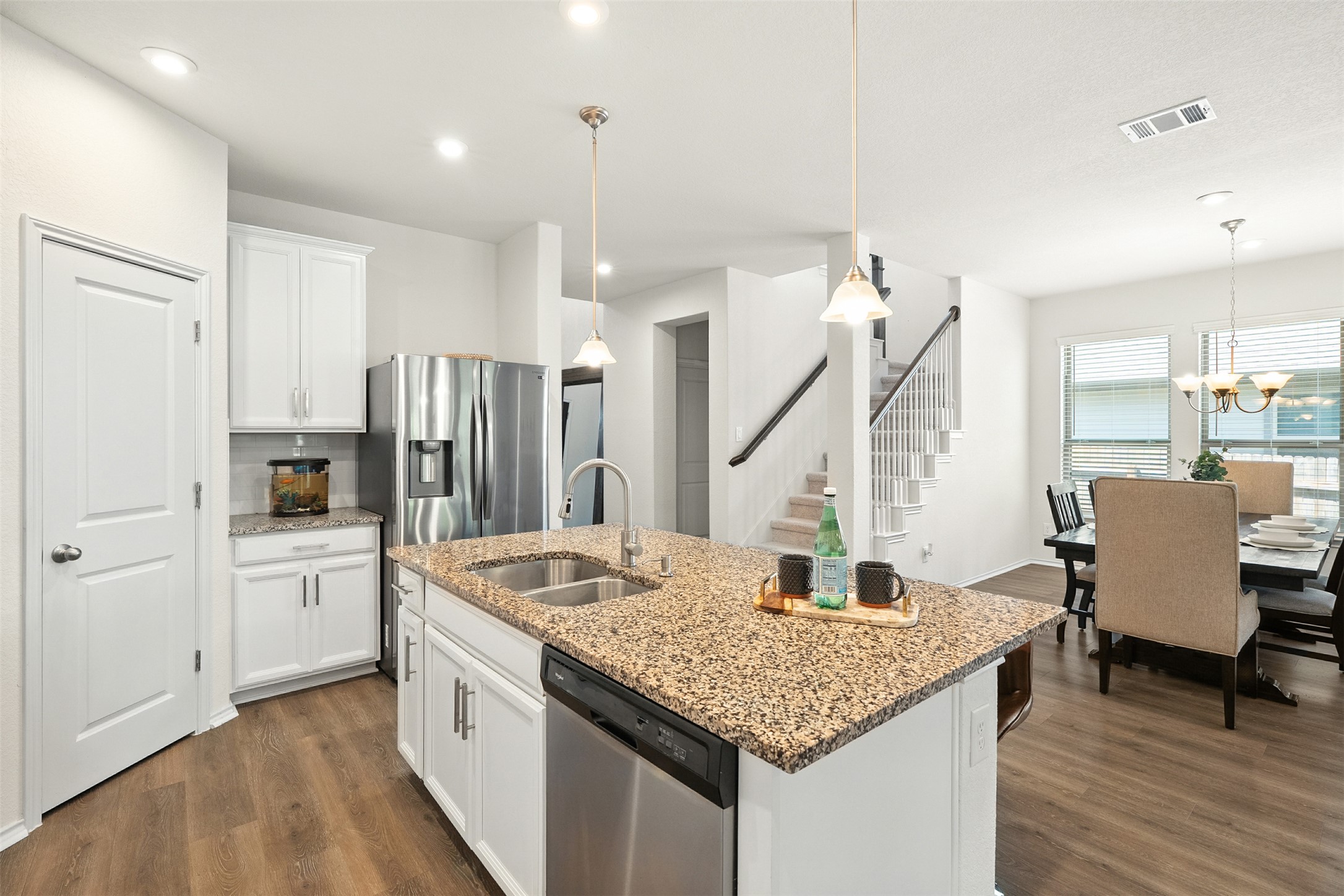 211 Brookside Street Hutto, TX 78634 - Photo 11 of 40 Kitchen with white cabinetry, appliances with stainless steel finishes, dark wood-style flooring, light stone counters, and decorative light fixtures