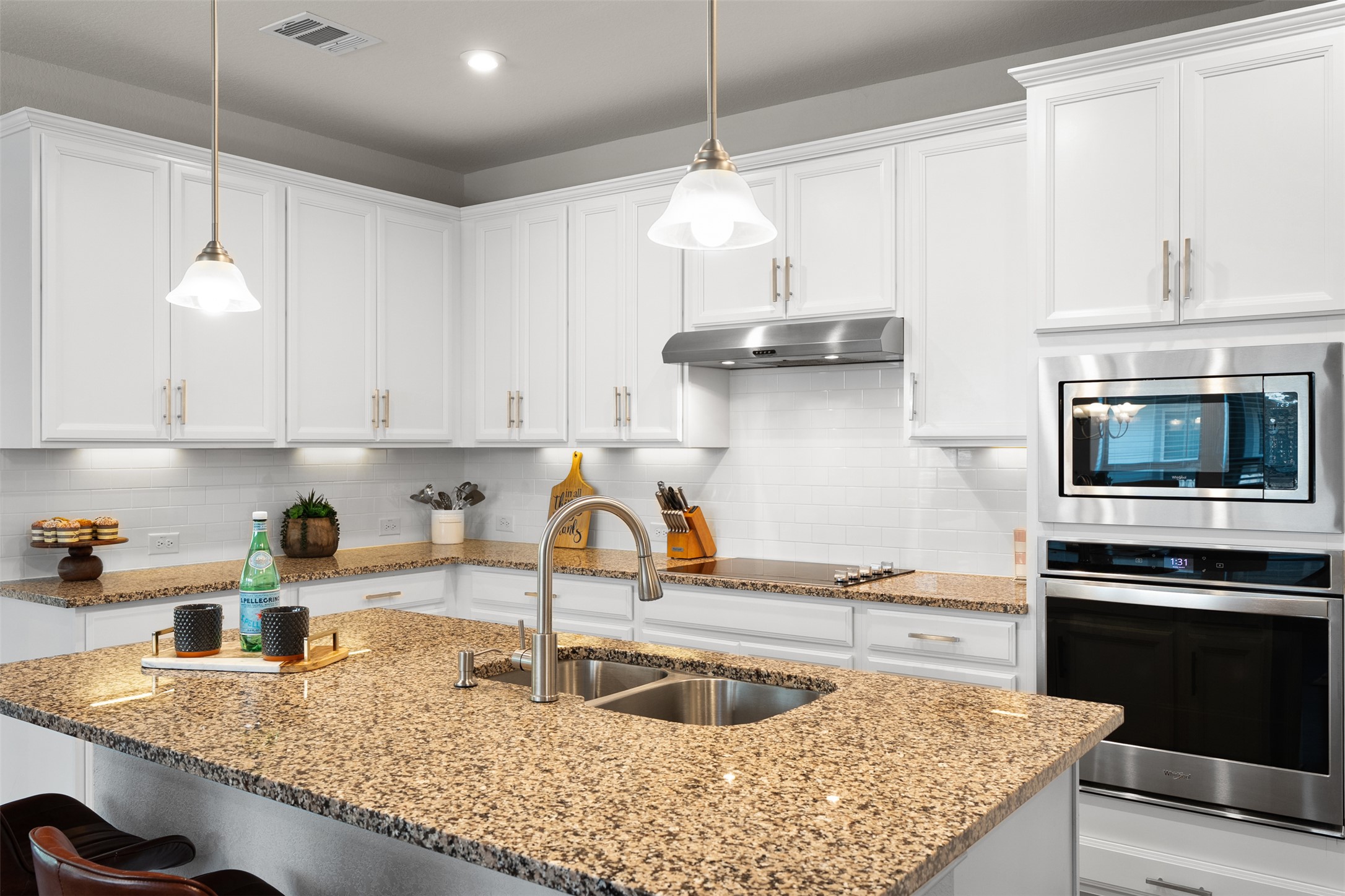 211 Brookside Street Hutto, TX 78634 - Photo 13 of 40 Kitchen featuring stainless steel appliances, white cabinets, tasteful backsplash, and a kitchen breakfast bar