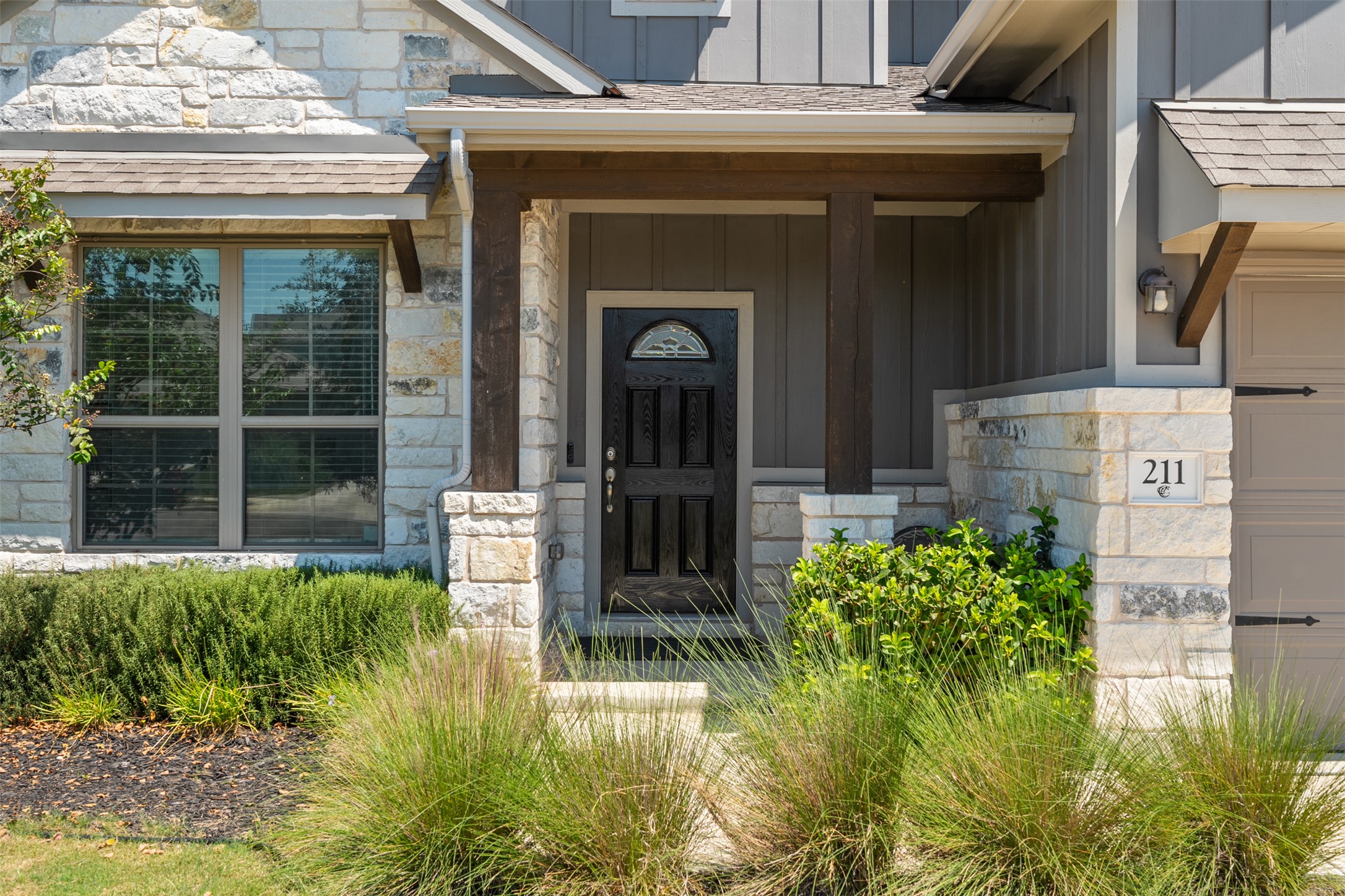 211 Brookside Street Hutto, TX 78634 - Photo 3 of 40 Doorway to property with board and batten siding, a porch, stone siding, roof with shingles, and a garage