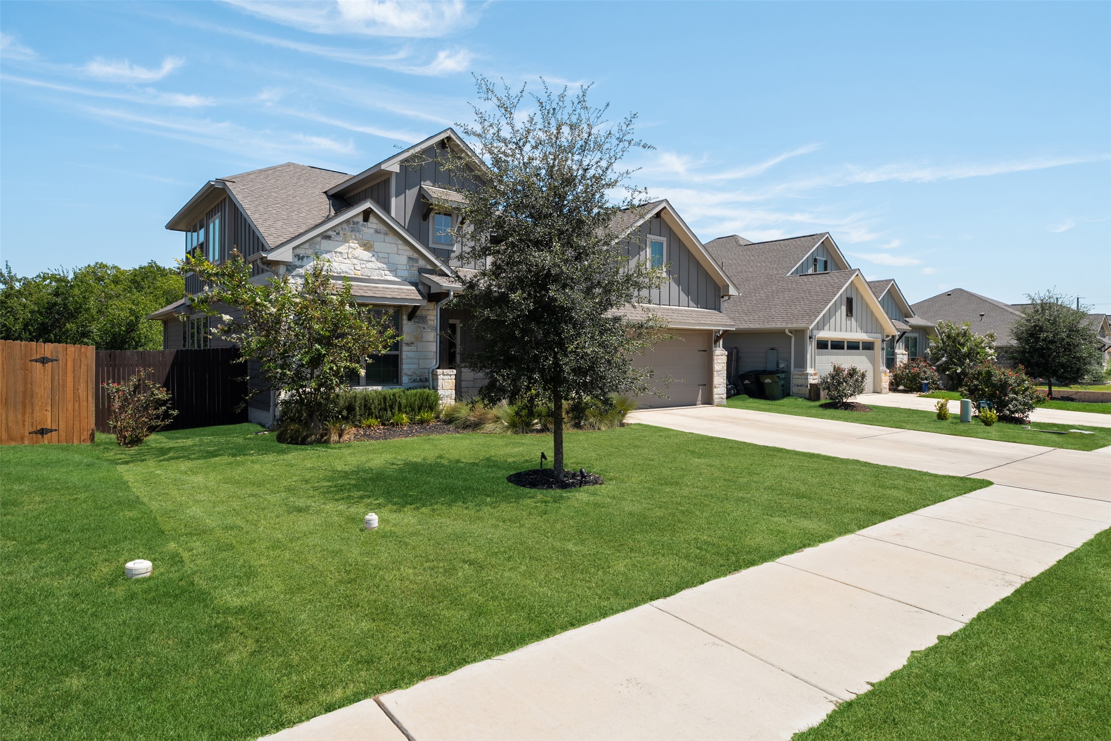 211 Brookside Street Hutto, TX 78634 - Photo 38 of 40 Craftsman-style house with board and batten siding, driveway, a shingled roof, stone siding, and a garage
