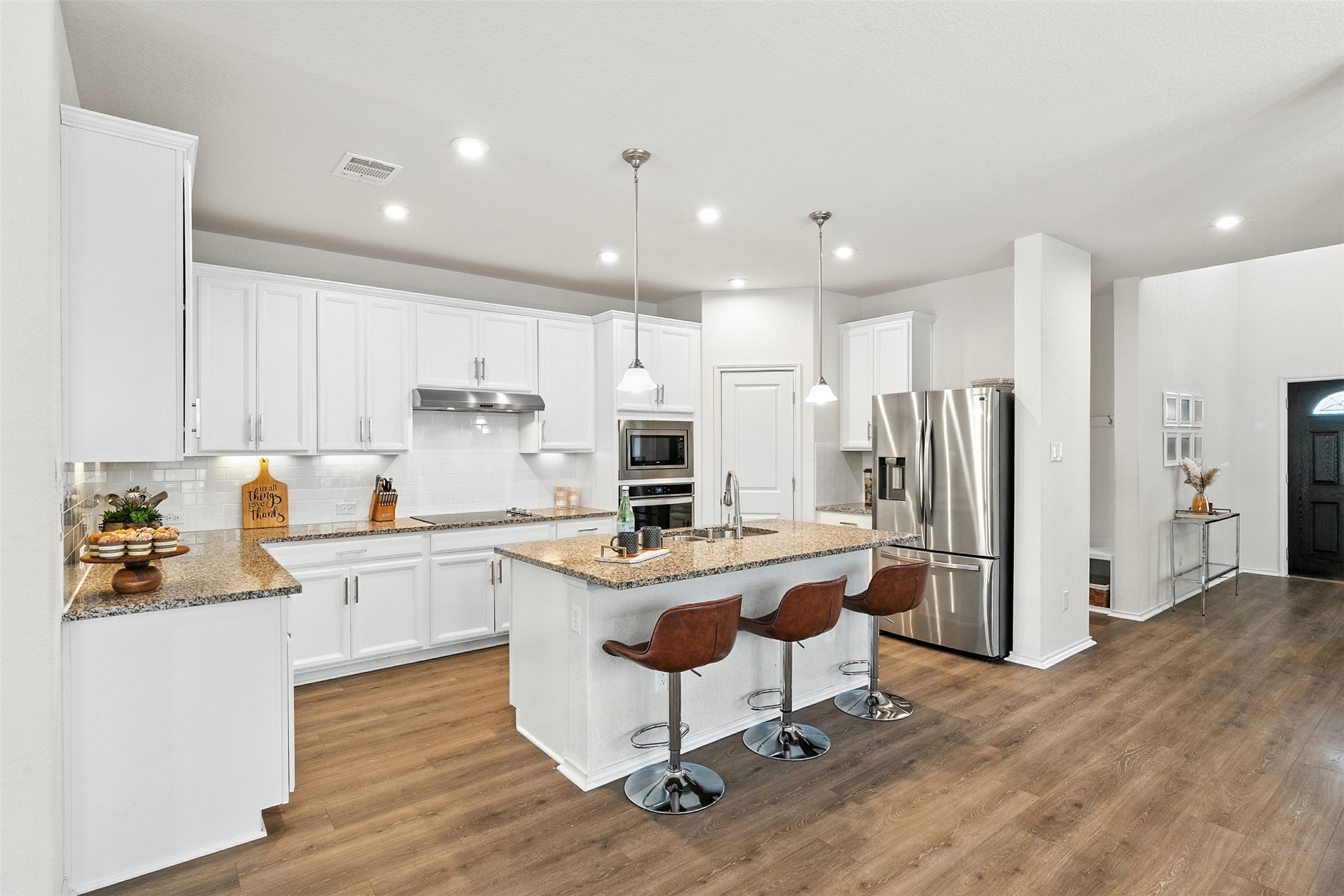 211 Brookside Street Hutto, TX 78634 - Photo 5 of 40 Kitchen with a kitchen bar, decorative backsplash, stainless steel appliances, a center island with sink, and decorative light fixtures