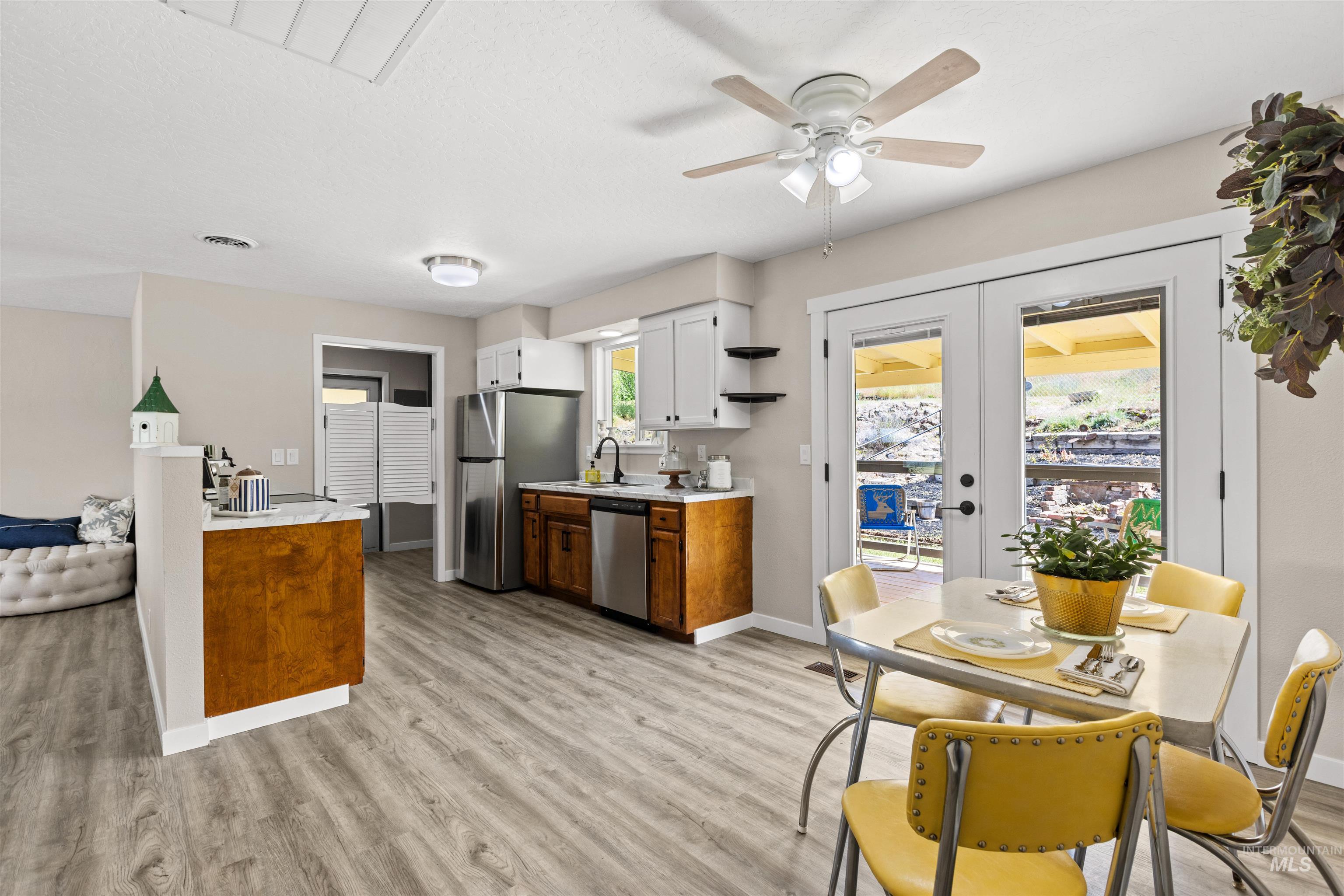 12184 Hill Road Payette, ID 83661 - Photo 17 of 35 Open-concept kitchen and dining area featuring wood-finish flooring, white cabinetry with dark hardware, stainless steel appliances, and French doors leading to an outdoor space
