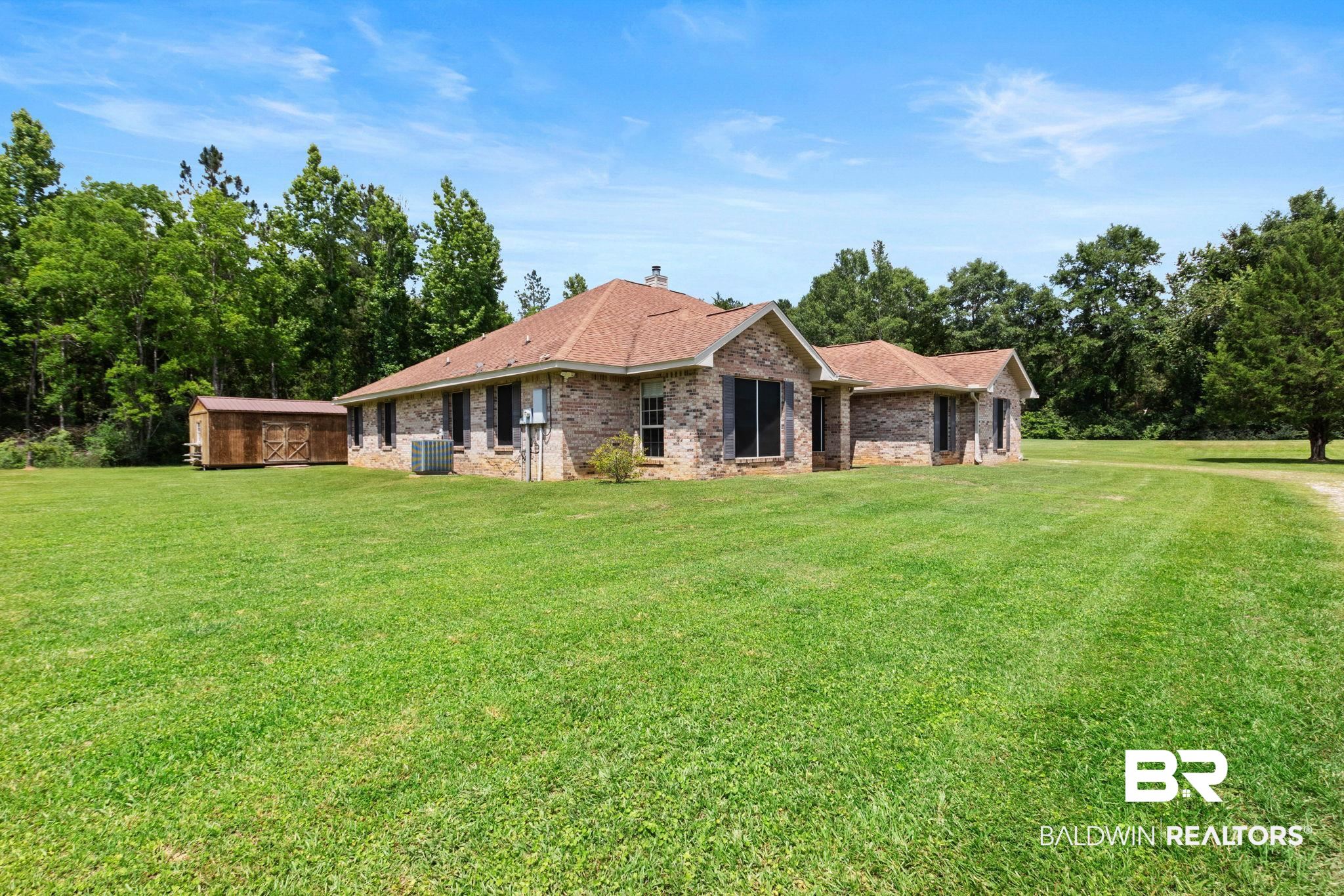 16151 Tolbert Road Bay Minette, AL 36507 - Photo 56 of 74 Expansive green lawn surrounding a brick residence with a brown shingle roof and a detached wood-sided storage shed