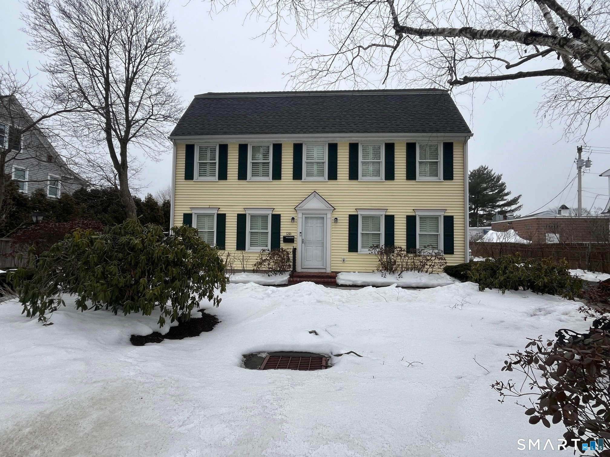 a view of a white house with a yard covered in snow
