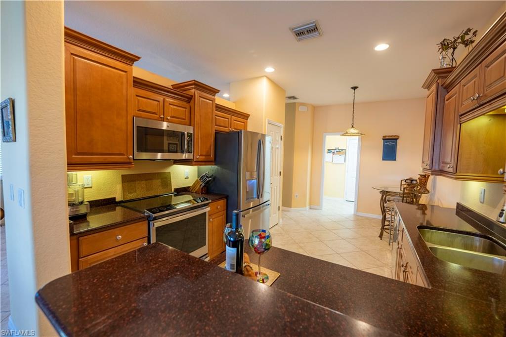 20007 Larino Loop Estero, FL 33928 - Photo 11 of 27 a kitchen with stainless steel appliances granite countertop a sink refrigerator and cabinets