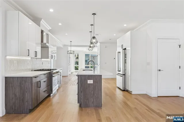 a large white kitchen with wooden floors and stainless steel appliances