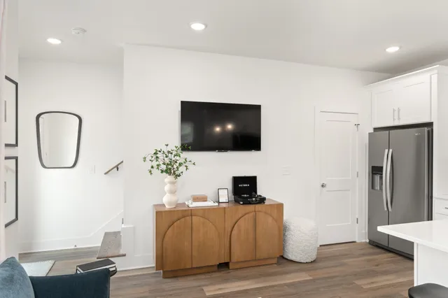 a living room with furniture a flat screen tv and a refrigerator