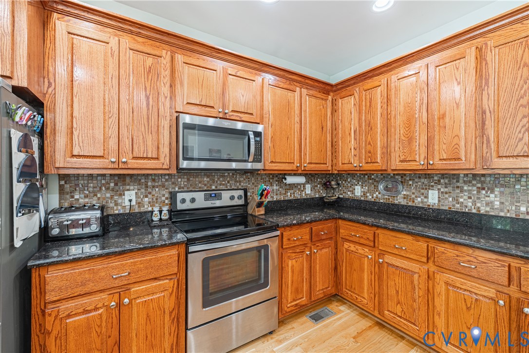 4789 Tatum Road Disputanta, VA 23842 - Photo 17 of 46 a kitchen with stainless steel appliances granite countertop a stove a sink dishwasher and a microwave oven with cabinets