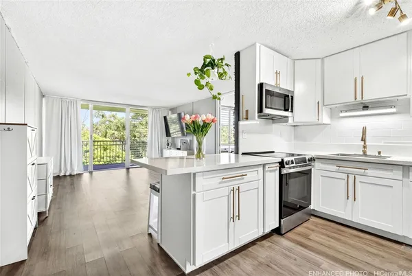 a white kitchen with stainless steel appliances granite countertop a stove a sink dishwasher and a microwave oven with wooden floor