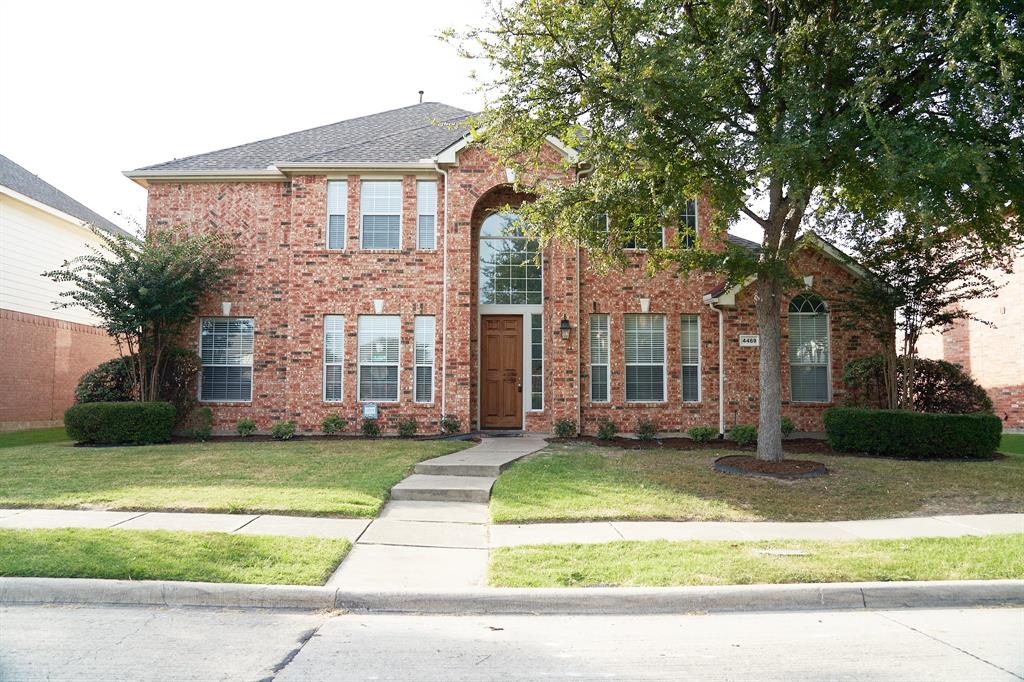 a view of a brick house with a yard and large trees