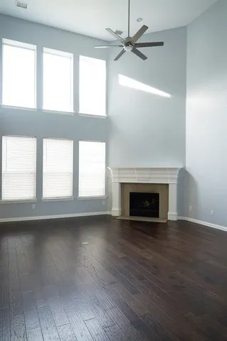 a view of an empty room with wooden floor fireplace and a window