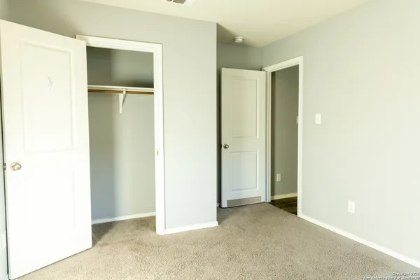 a view of an empty room with closet and a window
