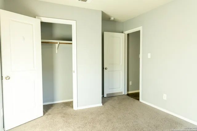 a view of an empty room with closet and a window