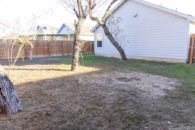 a view of a backyard with large trees and wooden fence