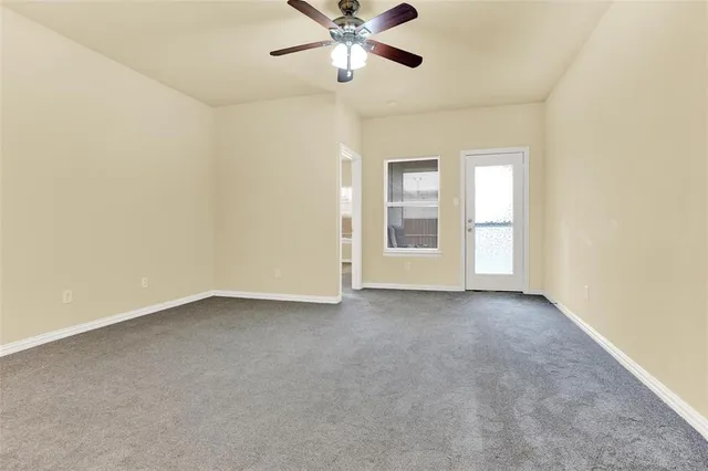 an empty room with window and ceiling fan