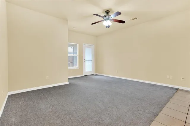 an empty room with a chandelier fan and a window