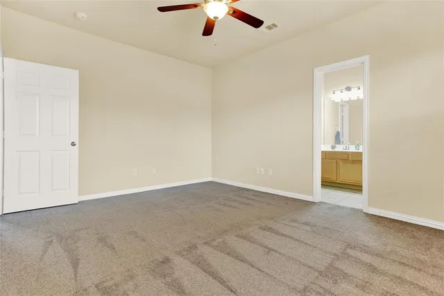 an empty room with chandelier fan and windows
