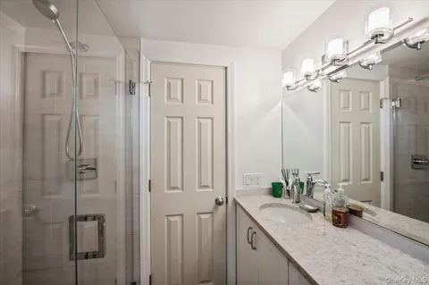 a bathroom with a granite countertop sink a mirror and a shower