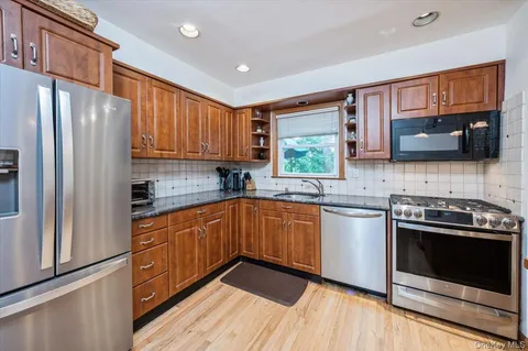 a kitchen with stainless steel appliances granite countertop wooden cabinets a stove a sink and a refrigerator