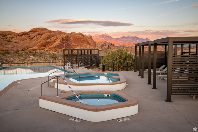 213 Lionsback Loop, Unit 38 Moab, UT 84532 - Photo 24 of 26 Outdoor aquatic area featuring multiple pools, two integrated spas with handrails, a paved deck, and a series of cabanas with horizontal slatted walls
