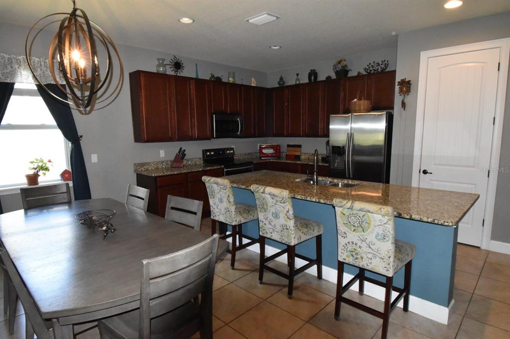 709 Calabria Way Howey-in-the-Hills, FL 34737 - Photo 6 of 26 a kitchen with a table chairs and a refrigerator