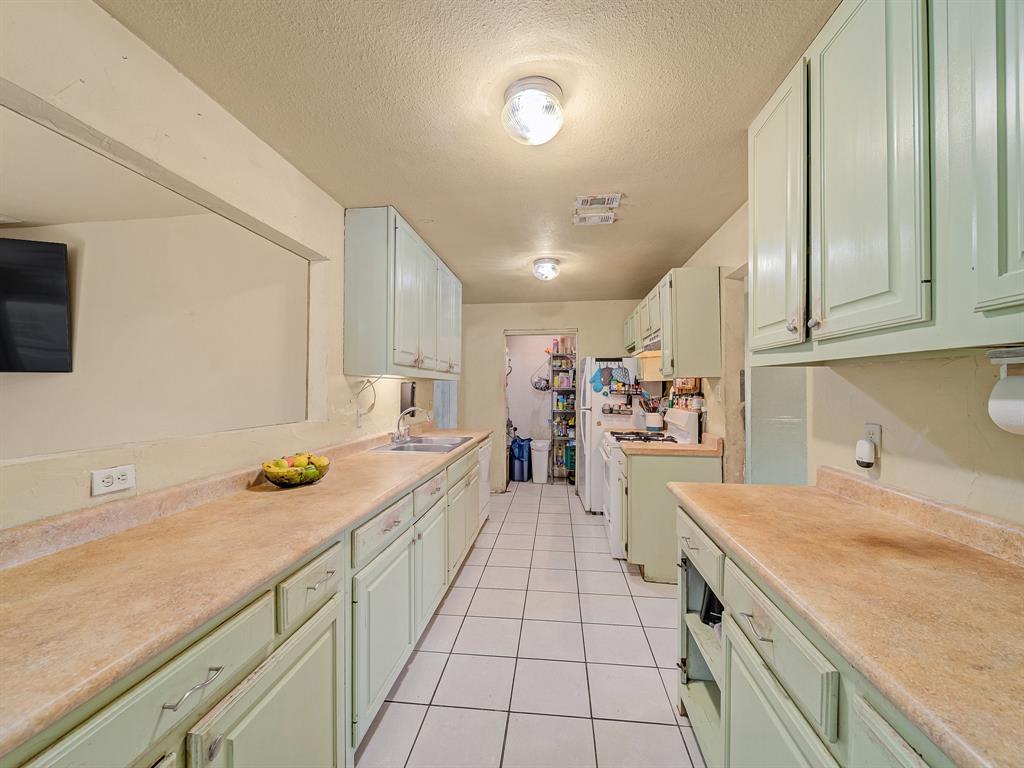 13833 Indian Wells Road Dallas, TX 75253 - Photo 19 of 39 Kitchen with green cabinets, light tile patterned floors, light countertops, a textured ceiling, and white appliances