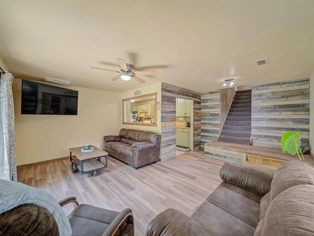 13833 Indian Wells Road Dallas, TX 75253 - Photo 24 of 39 Living area featuring a ceiling fan, light wood-style flooring, stairs, and an accent wall. Stairs lead to 2nd floor