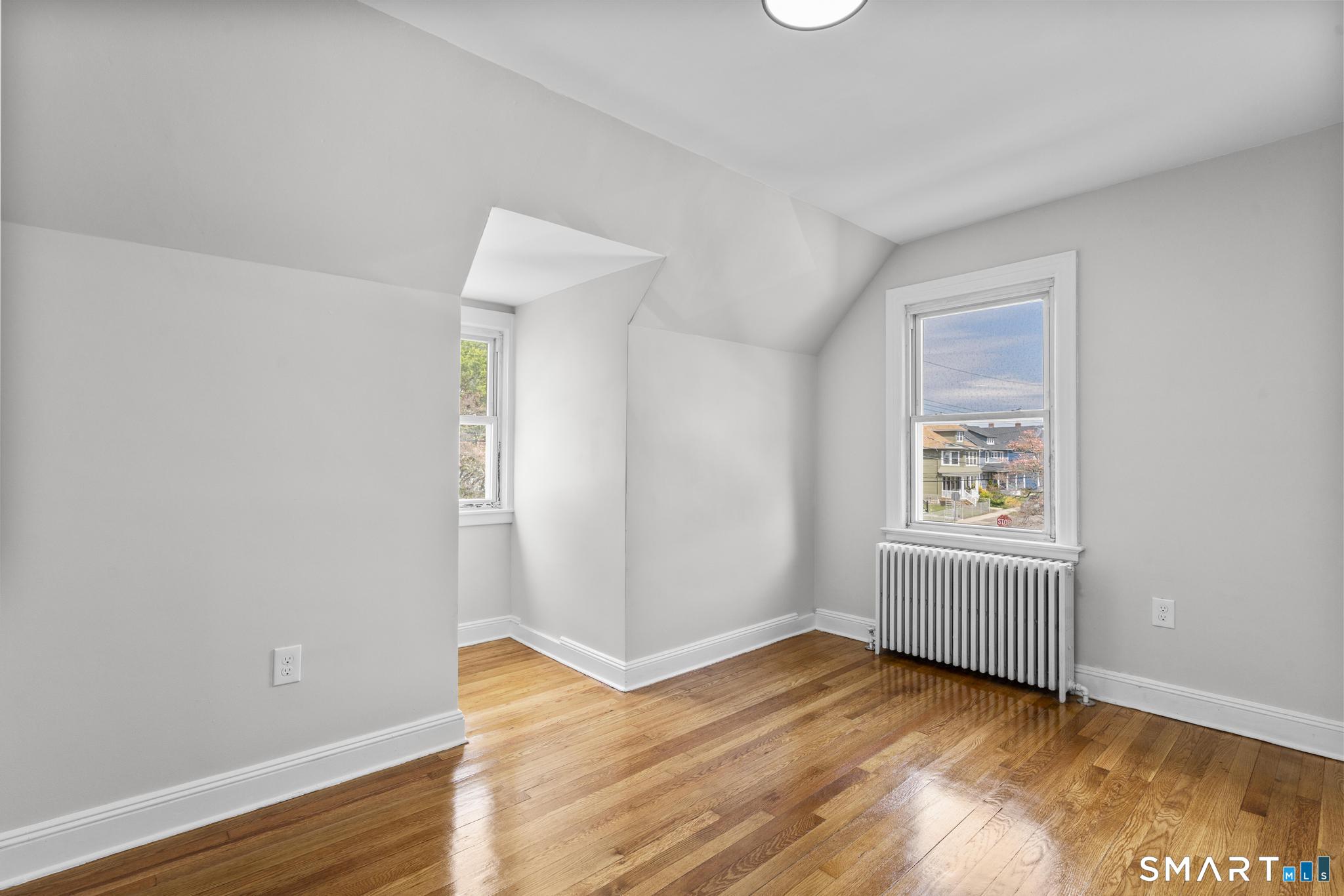 94 3rd Street Hamden, CT 06514 - Photo 22 of 30 an empty room with wooden floor cabinet and windows