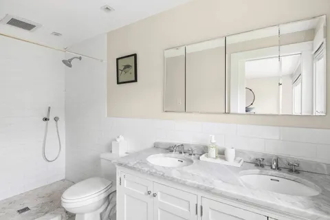 a bathroom with a granite countertop sink a toilet and a mirror