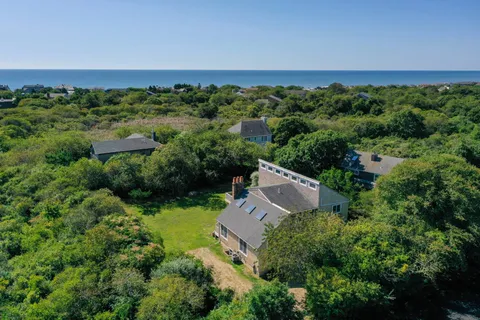 an aerial view of a house with yard and trees all around