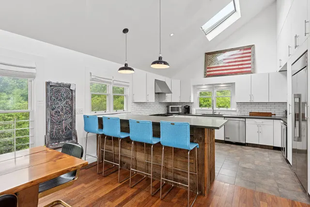 a kitchen with stainless steel appliances granite countertop a stove a sink dishwasher a dining table and chairs with wooden floor