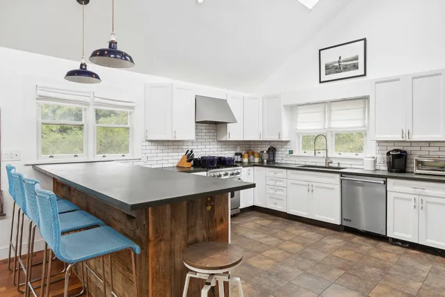 a kitchen with stainless steel appliances granite countertop a stove a refrigerator a sink a dining table and chairs with wooden floor