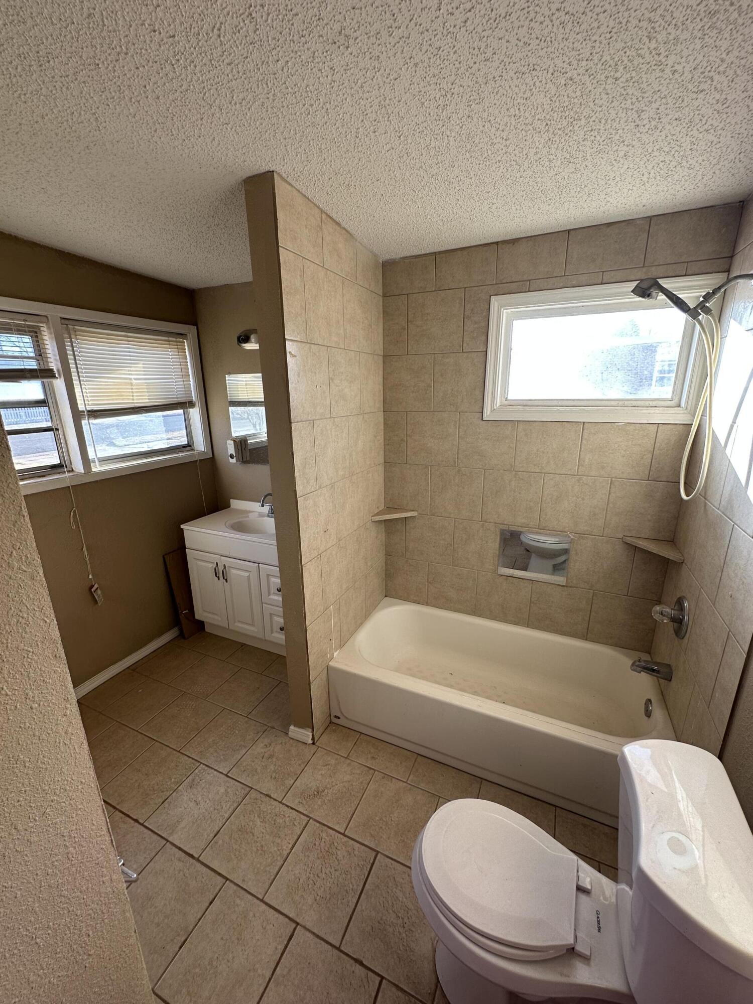 2416 47th Street Lubbock, TX 79412 - Photo 13 of 23 a bathroom with a toilet a sink a bath tub and mirror