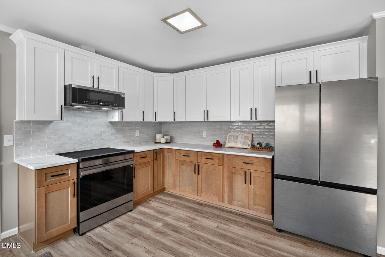 2734 Spencer Street Durham, NC 27705 - Photo 25 of 61 a kitchen with stainless steel appliances granite countertop a stove a refrigerator and a stove top oven