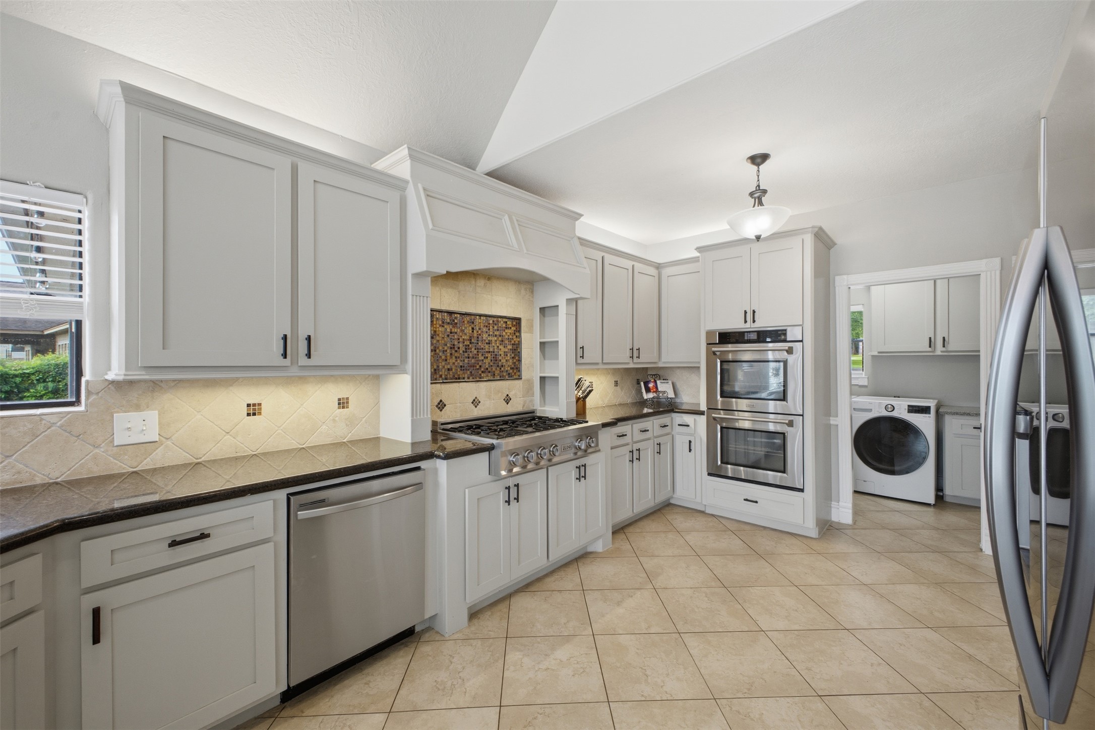 12710 Aries Loop Willis, TX 77318 - Photo 11 of 40 The kitchen features light-colored cabinetry, stainless steel appliances including a built-in double oven and a dishwasher, and a range with a decorative tile backsplash