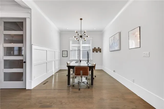 a dining room with chandelier and wooden floor