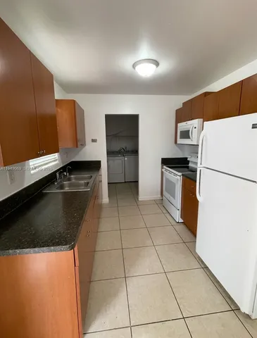 a kitchen with granite countertop a refrigerator a stove and a sink