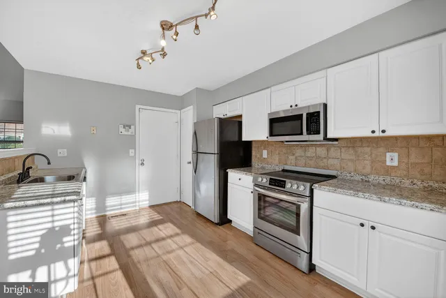 a kitchen with granite countertop a stove a sink and a microwave