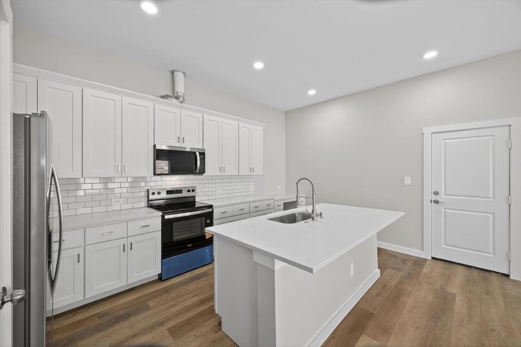 122 Wood Street, Unit A Princeton, TX 75407 - Photo 8 of 29 a kitchen with a sink a stove a refrigerator and white cabinets