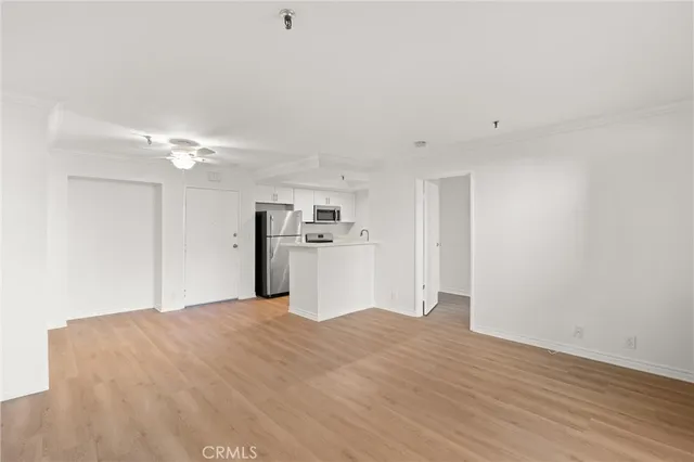 a view of a big room with wooden floor and a kitchen